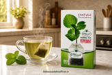 بسته چای کیسهای نعناع عباسزاده اصل ۲۰ عددی در کنار برگهای تازه و باطراوت نعناع فلفلی